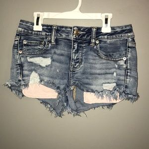 Distressed jean shorts with light pink pockets